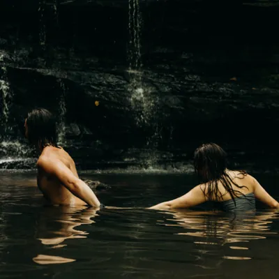 man leading a women through the water in a lagoon